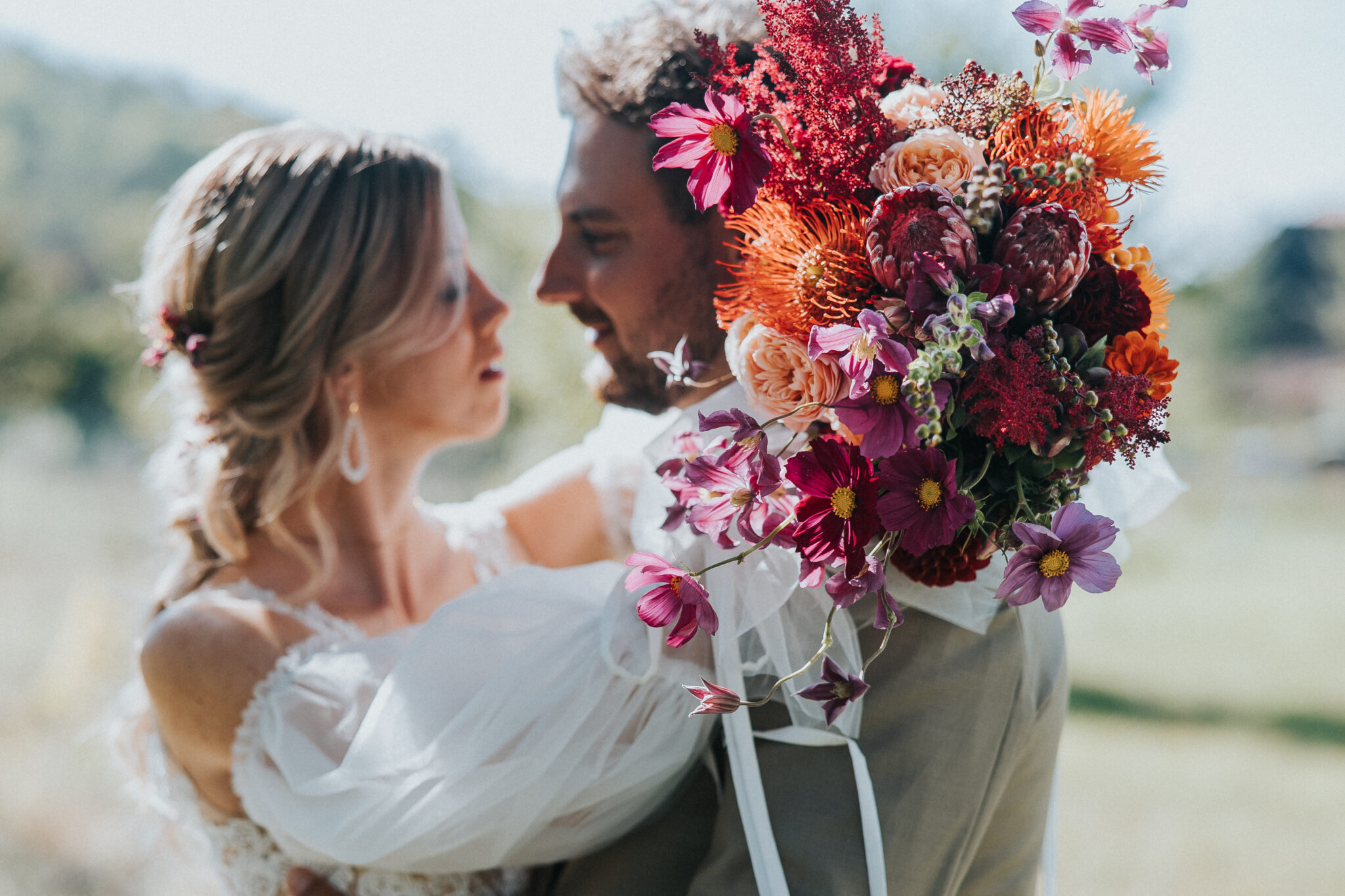 Brautpaar beim Fotoshooting mit einem herbstlichen Brautstrauß im Vordergrund bei ihrer Autumn Sunset Wedding